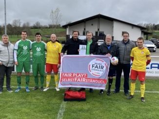 Fußballmannschaft präsentiert Fair-Play-Banner.