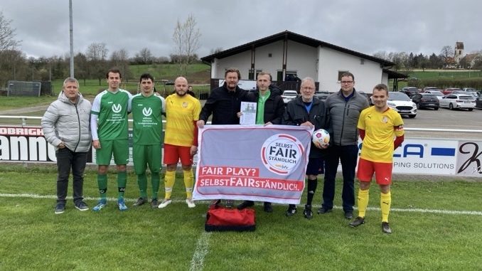 Fußballmannschaft präsentiert Fair-Play-Banner.